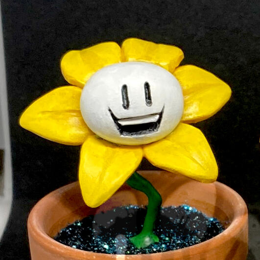 A tiny sculpture of Flowey the flower in a little terra cotta pot!