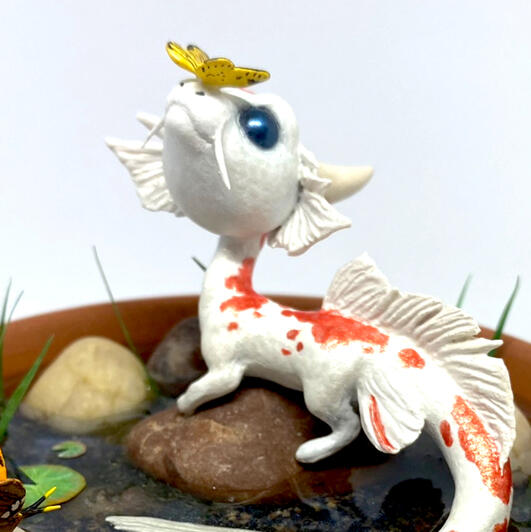 A sculpture of a tiny koi dragon with a butterfly on its nose.